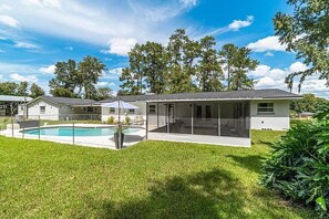 Una casa moderna con piscina, terraza cubierta y césped bien cuidado.