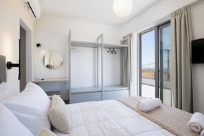 A hotel room with a bed, a bedside table, a mirror, a wardrobe, and a window with curtains. - Villa Mino Mare (Mylopotamos)