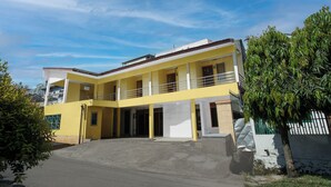 A two-story yellow building with a flat roof, a covered entrance, and a small balcony on the upper floor. - OYO 94908 Demang Kostel (Palembang)