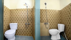 A bathroom with two toilets, a shower, and patterned walls. - OYO 94908 Demang Kostel (Palembang)
