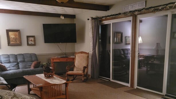 A cozy living room with a sofa, two rocking chairs, a coffee table, and a ceiling fan. A sliding glass door leads to a balcony. - Peaceful riverfront home, 3 bedroom,  sleeps 6, in Elkhart. (Elkhart)