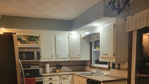 A kitchen with white cabinets, a stainless steel refrigerator, a dishwasher, and a microwave. - Peaceful riverfront home, 3 bedroom,  sleeps 6, in Elkhart. (Elkhart)