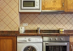 A kitchen with a microwave, toaster, kettle, washing machine, and oven. - La Viña Rural Apartments (Apartment number 4) (Cangas de Onís)