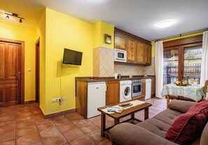 A compact living space with a kitchen, a dining area, and a sofa. - La Viña Rural Apartments (Apartment number 4) (Cangas de Onís)
