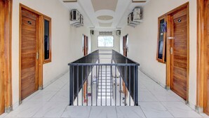 A corridor with wooden doors, air conditioning units, and a tiled floor. - OYO 94919 Nay Guesthouse Dan Kost (Surakarta)