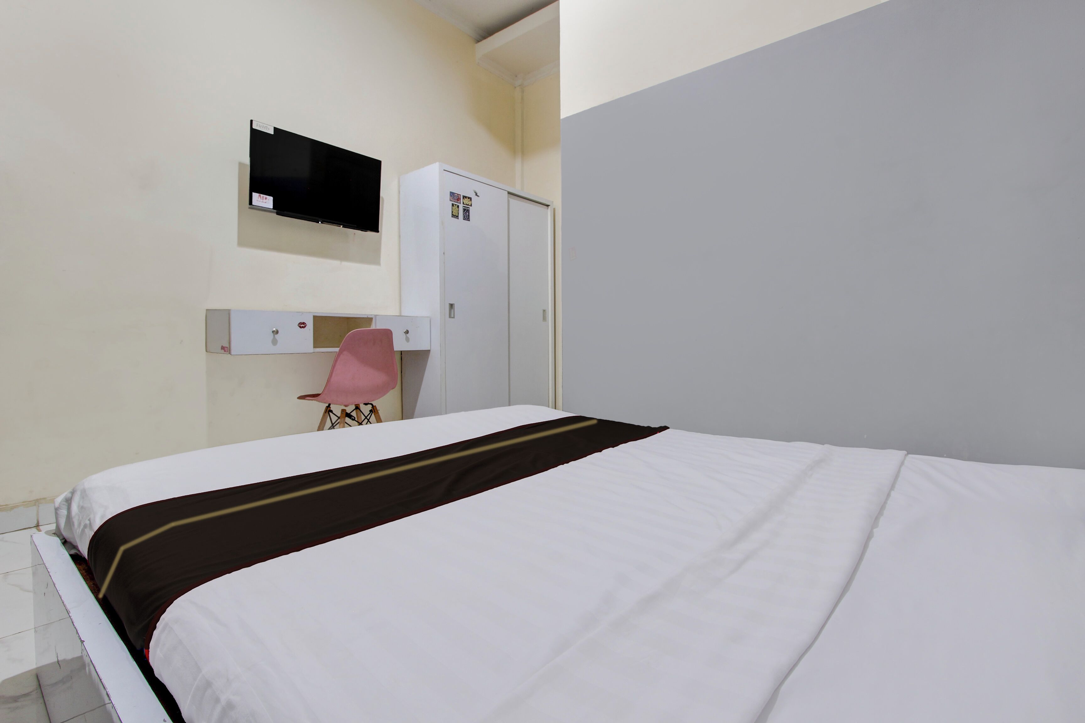 A bedroom with a bed, a desk, a chair, and a wardrobe.