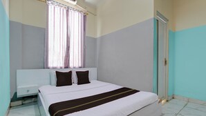 A neatly made bed with white and brown bedding, a nightstand with a drawer, and a window with curtains. - OYO 94919 Nay Guesthouse Dan Kost (Surakarta)