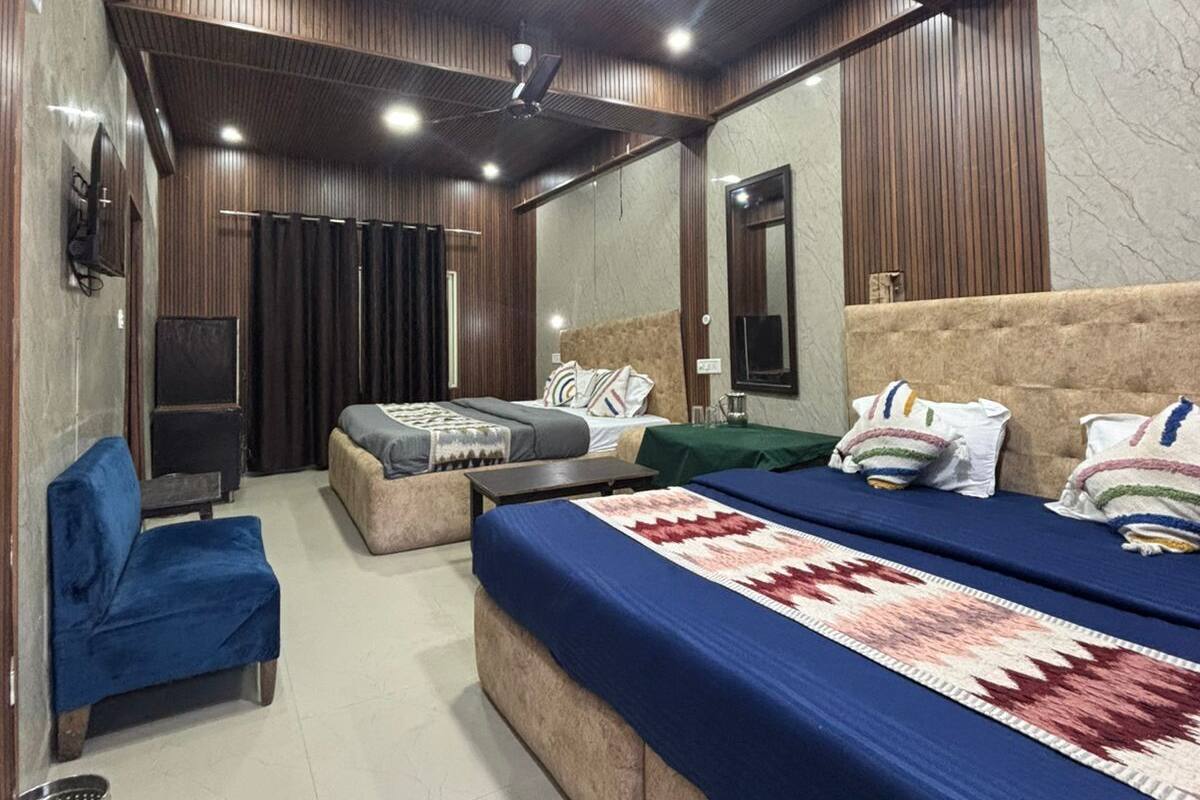 A modern hotel room with a large bed, a sofa, a small table, and a mirror.