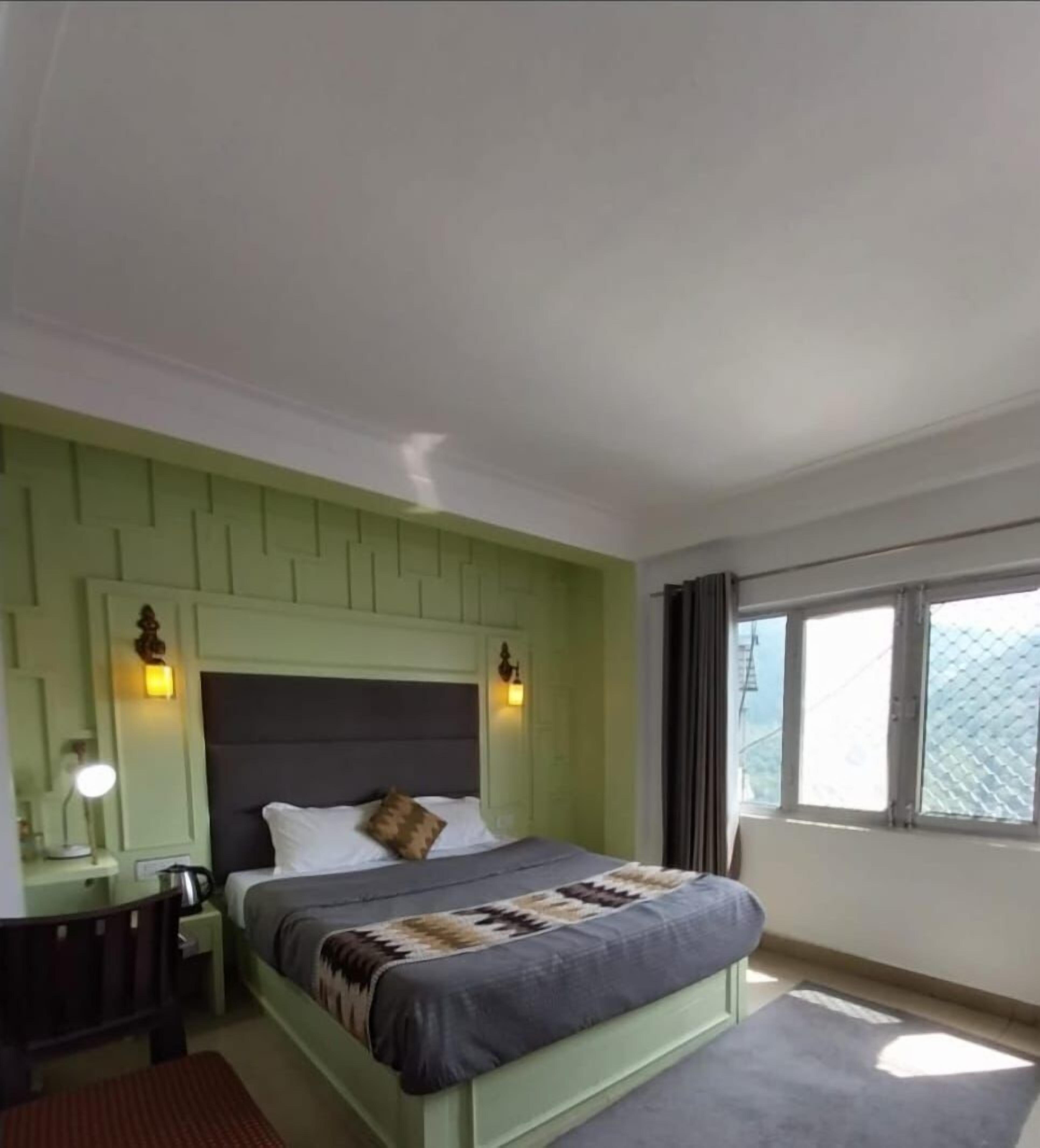 A hotel room with a bed, a desk, a chair, and a window with curtains.