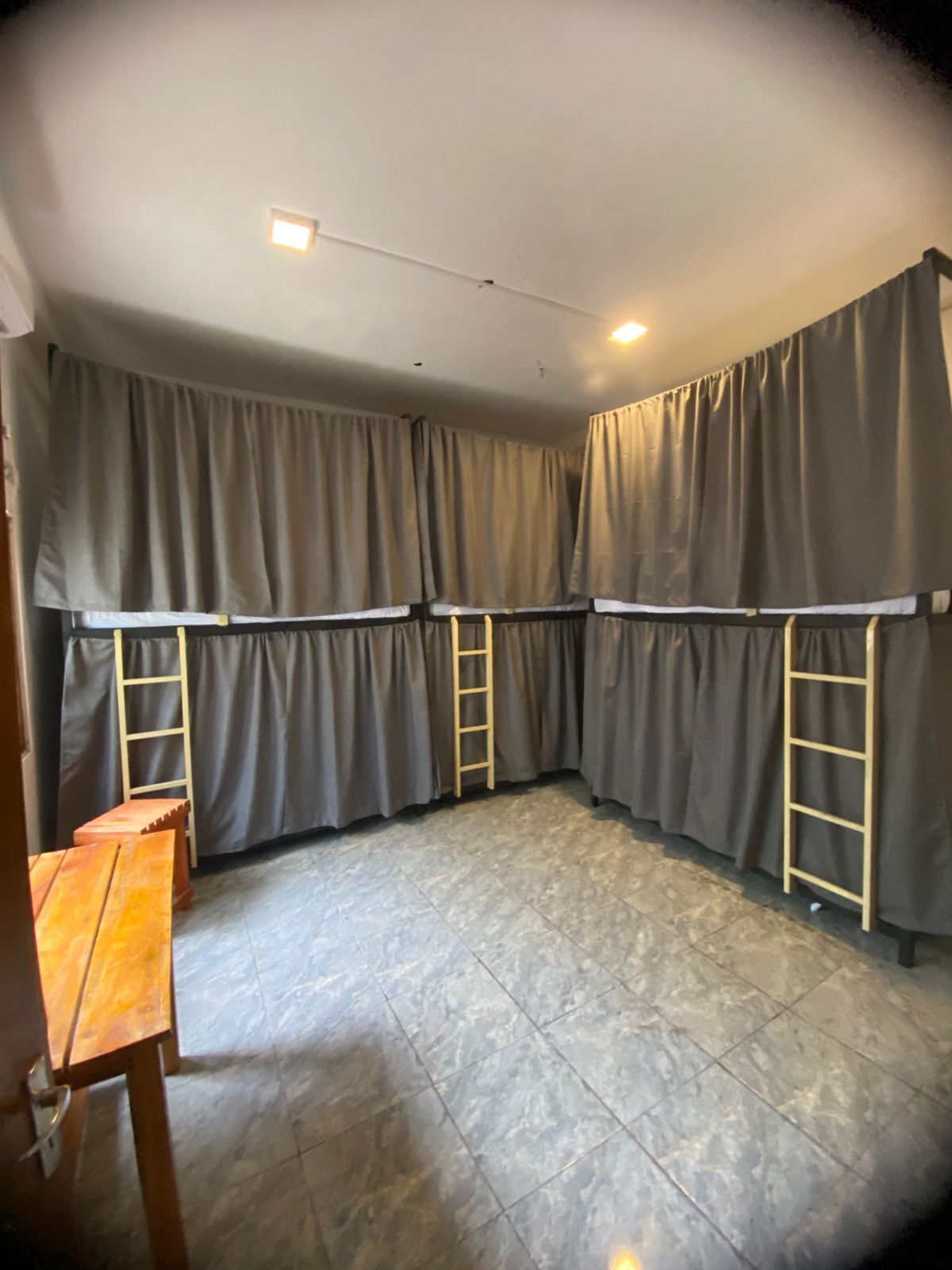 A room with a tiled floor, grey curtains, and two wooden ladders.