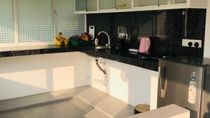 Une cuisine moderne avec des meubles blancs, un plan de travail noir et deux suspensions en osier.