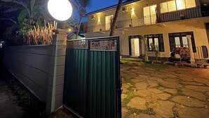 Un immeuble de deux étages doté d’un balcon, d’une entrée sécurisée par un portail et d’un lampadaire bien éclairé.