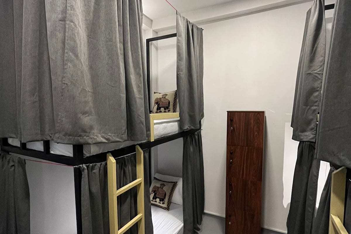 A dormitory room with bunk beds, a ladder, a wardrobe, and a mirror.