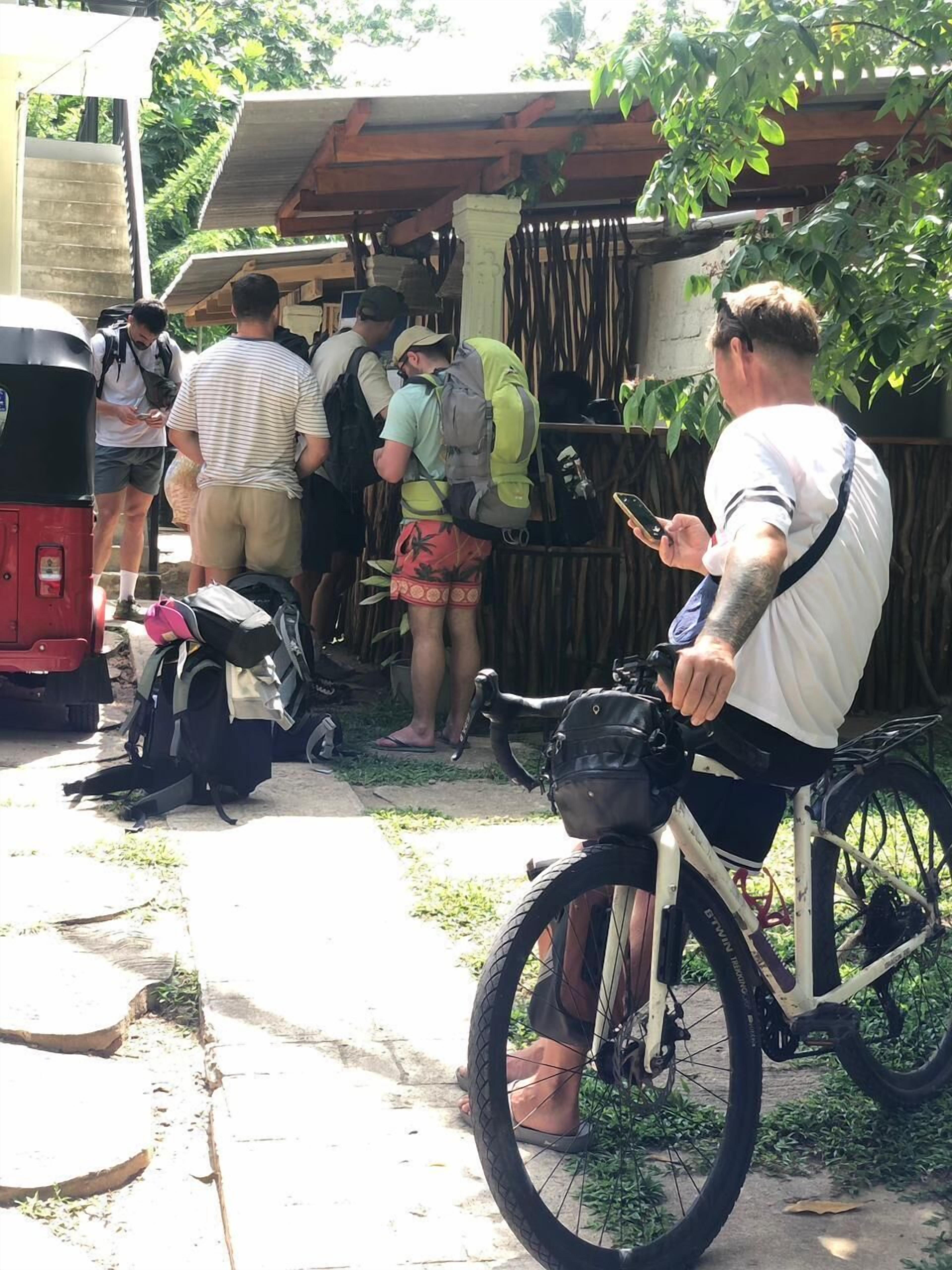 A group of people gathered around a vehicle, possibly a van, with a bicycle parked nearby.