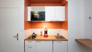 Cocina compacta con microondas, cafetera y lavabo.