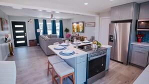 Een moderne keuken met een centraal eiland, roestvrijstalen apparatuur en een eethoek in blauw-witte kleurstelling.