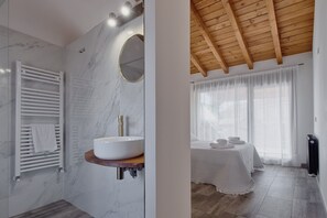 Un baño moderno con pared de mármol, un lavamanos blanco y un perchero.