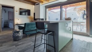 Eine moderne Küche mit Barbereich, Holzbalkendecke und großem Fenster mit Blick auf eine Terrasse.