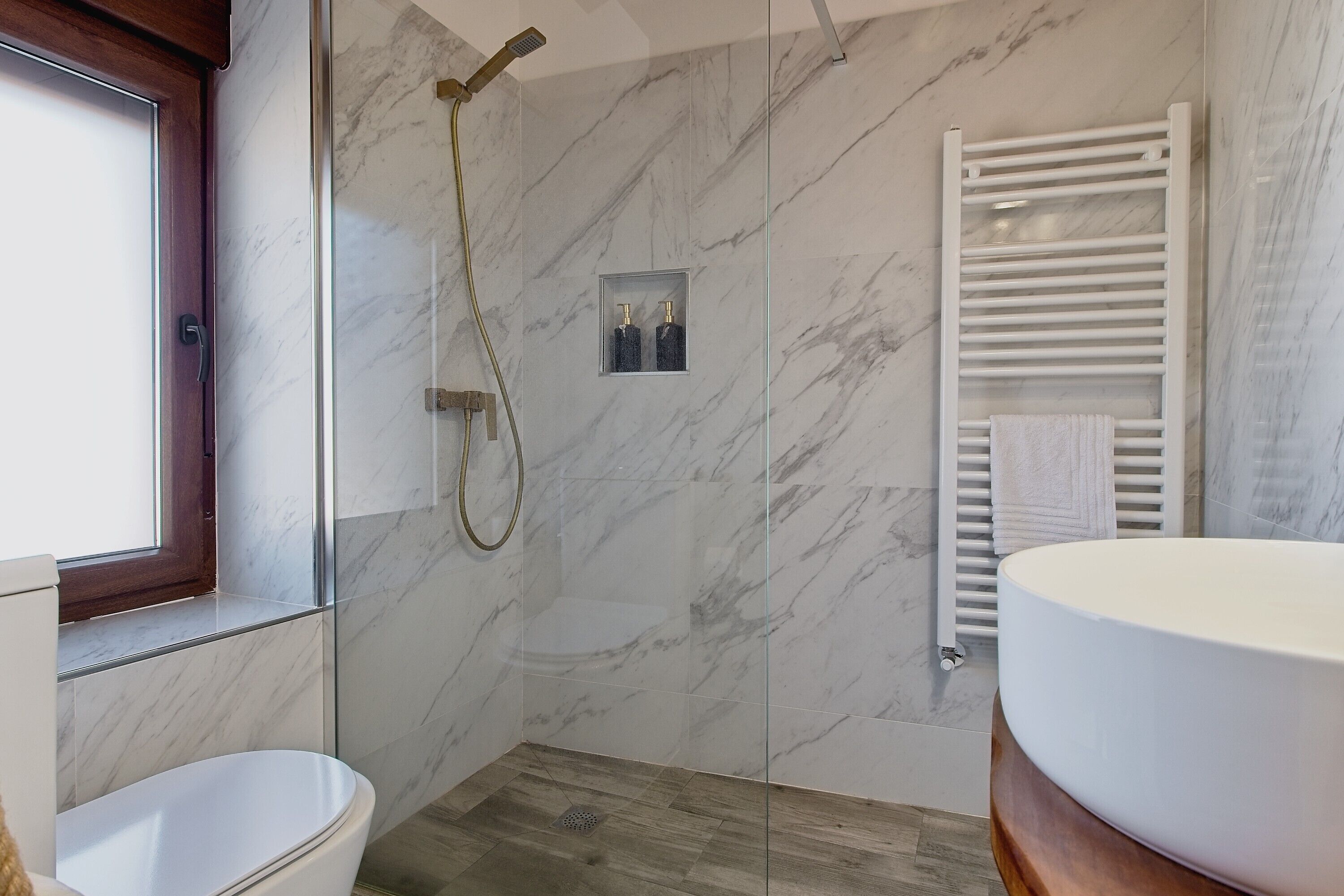 A bathroom with a toilet, a shower, a glass-enclosed medicine cabinet, and a white sink.