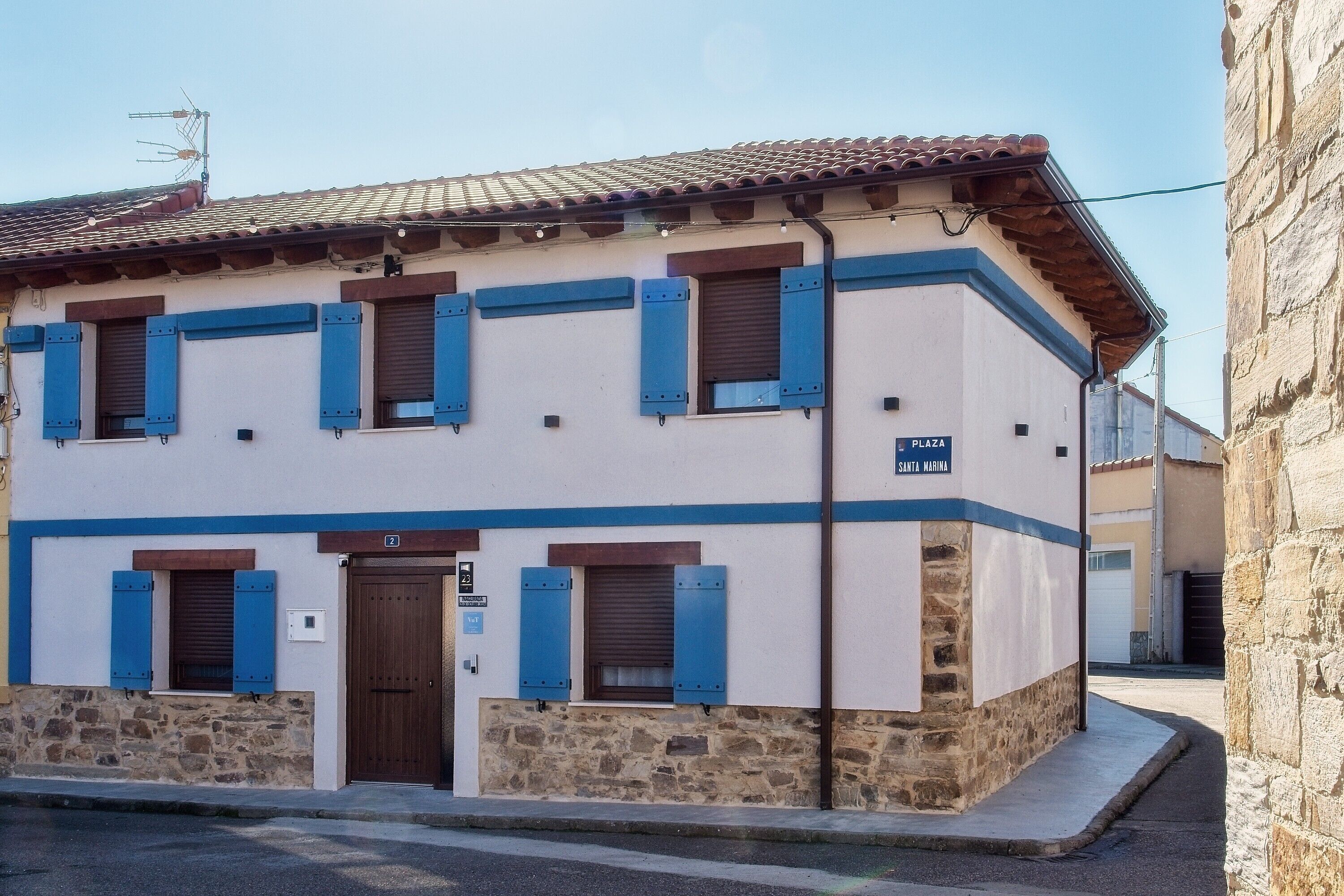 A building with a stone base, a tiled roof, and blue shutters.