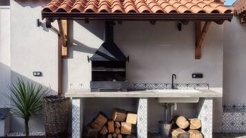 An outdoor kitchen with a chimney, a sink, and a tiled backsplash.