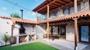 Eine Terrasse mit Grill, Esstisch und einer Steinsäule.