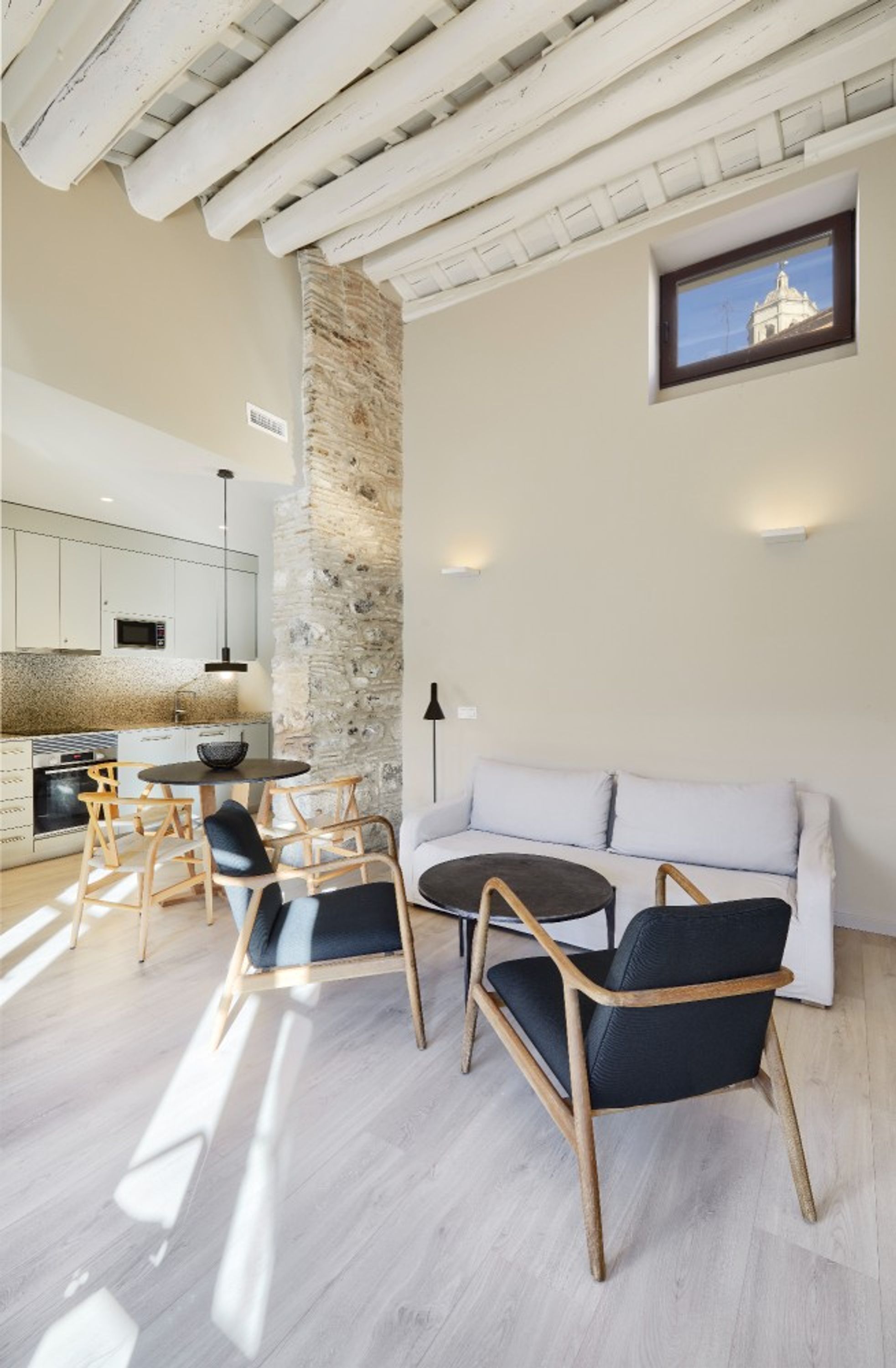 Una cocina moderna con armarios blancos, una pared de acento de piedra y un comedor con una mesa redonda y sillas.