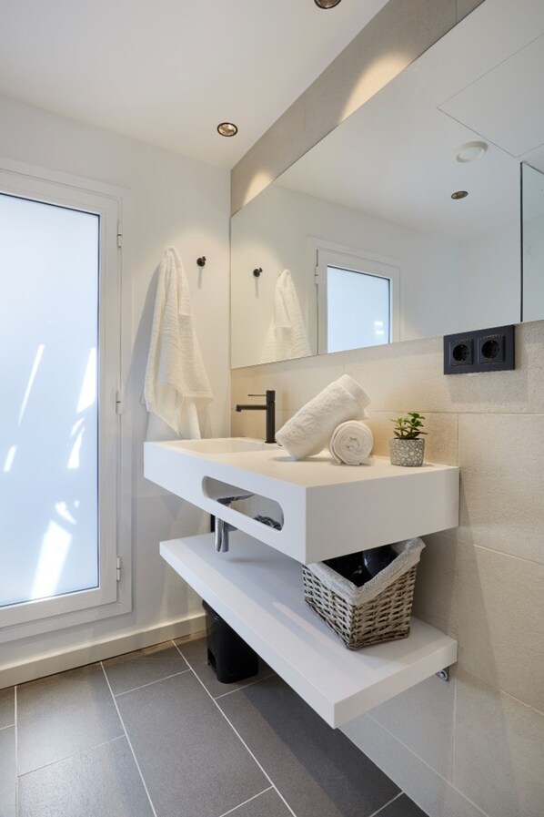 Un baño moderno con tocador blanco, un espejo grande y un perchero para toallas.