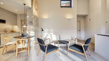 A modern kitchen with a stone accent wall, a dining area with wooden chairs and a round table, and a small window above the seating area.
