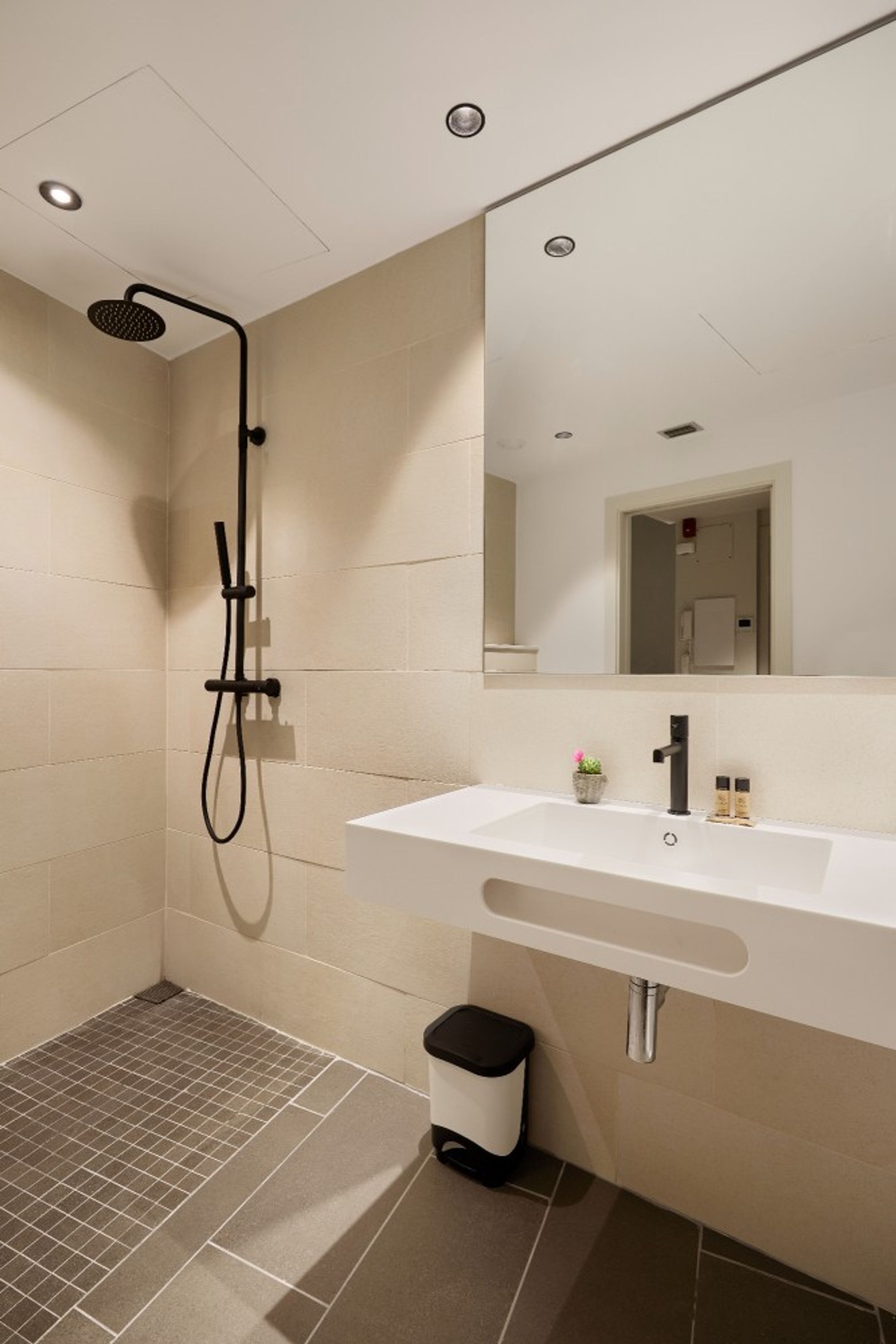Un baño moderno con ducha, lavabo y espejo.