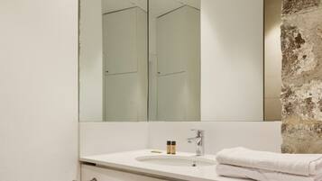 A bathroom with a large mirror, a sink, and a towel rack.