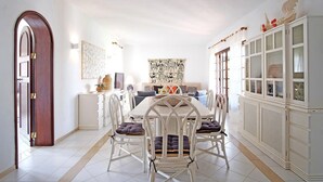A dining area with a white table and chairs, a cabinet with glass doors, and artwork on the walls. - VV Beautiful Villa w/pool | A/C | VILAMOURA! (Quarteira)