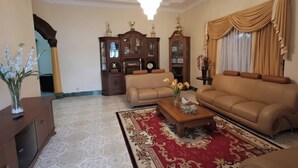A living room with a chandelier, two sofas, a coffee table, and a patterned rug. - OYO 94930 Yetelu Guest House (Bontang)