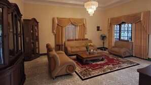 A spacious living room with a chandelier, leather sofas, a coffee table, and a patterned rug. - OYO 94930 Yetelu Guest House (Bontang)