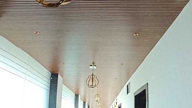 A long, well-lit hallway with a modern ceiling design, including a prominent chandelier and recessed lighting. - Hotel Mitra Inn (Pushkar)