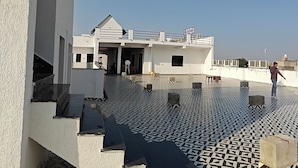 A building with a tiled floor and a staircase leading to a covered entrance. - Hotel Mitra Inn (Pushkar)