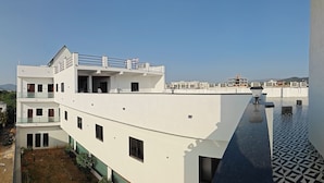 A modern multi-story building with balconies, a flat roof, and a patterned floor. - Hotel Mitra Inn (Pushkar)
