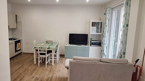 Ein kompakter Wohnraum mit Küchenzeile, Essbereich und einer Couch.