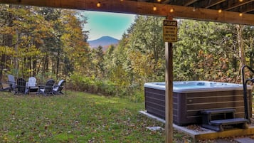 A hot tub under a wooden pergola with a sign instructing to shower before entering.