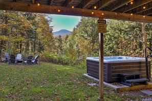 Un jacuzzi debajo de una pérgola de madera con un cartel que indica ducharse antes de entrar.