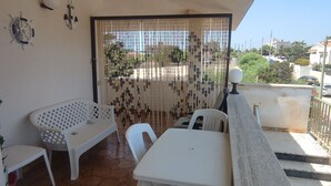 A balcony with a table and two chairs, a decorative curtain, and a view of the neighborhood. - Beachfront apartment with panoramic view (San Lorenzo)