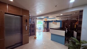 A hotel reception area with a modern design, including a reception desk, a wooden door, and a tiled floor. - Hotel Arya Residency Rabale (Navi Mumbai)