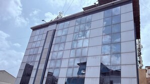 A modern building with a glass facade and a sign in a local language. - Hotel Arya Residency Rabale (Navi Mumbai)