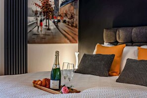A bed with a bottle of champagne, glasses, and croissants on a tray, pillows, and a framed picture on the wall. - The Milton Smart Spacious 3-Bed Bournemouth (Bournemouth)