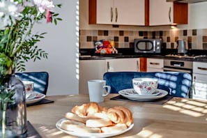 A dining table with croissants, a floral cup, and a white mug. - The Milton Smart Spacious 3-Bed Bournemouth (Bournemouth)