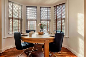 A dining area with a round table, four chairs, and a vase of flowers. - The Milton Smart Spacious 3-Bed Bournemouth (Bournemouth)