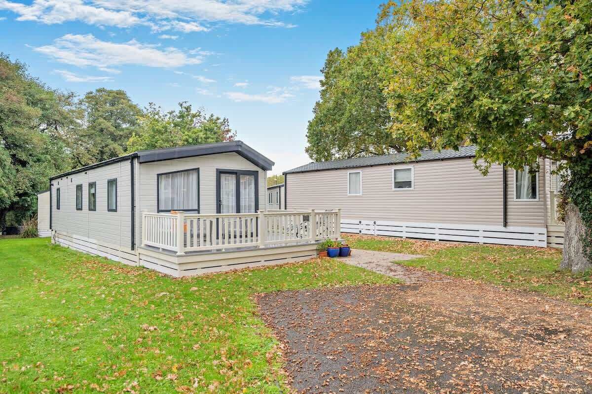 A mobile home with a porch and a fenced yard.