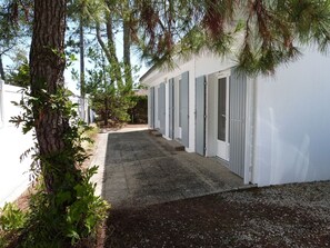 Eine Reihe weißer Gebäude mit grauen Türen, ein Kiesweg und umliegendes Grün.