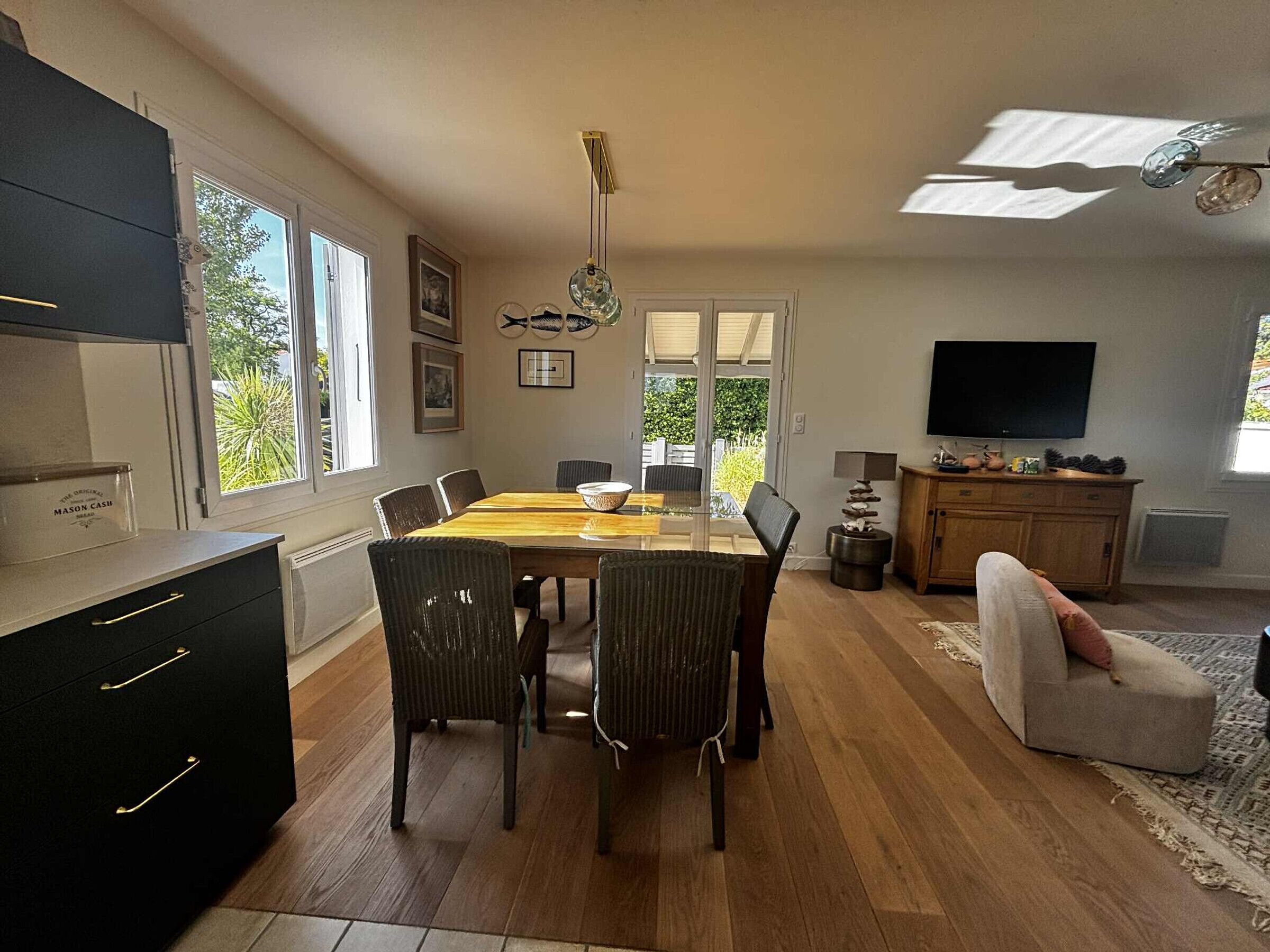 A modern kitchen with a dining area, a television, and a view of the outdoors.