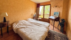 A bedroom with a large bed, a desk, a chair, and a window with curtains. - Duplex with Terrace and Private Beach Access, Garage Included (Évian-les-Bains)